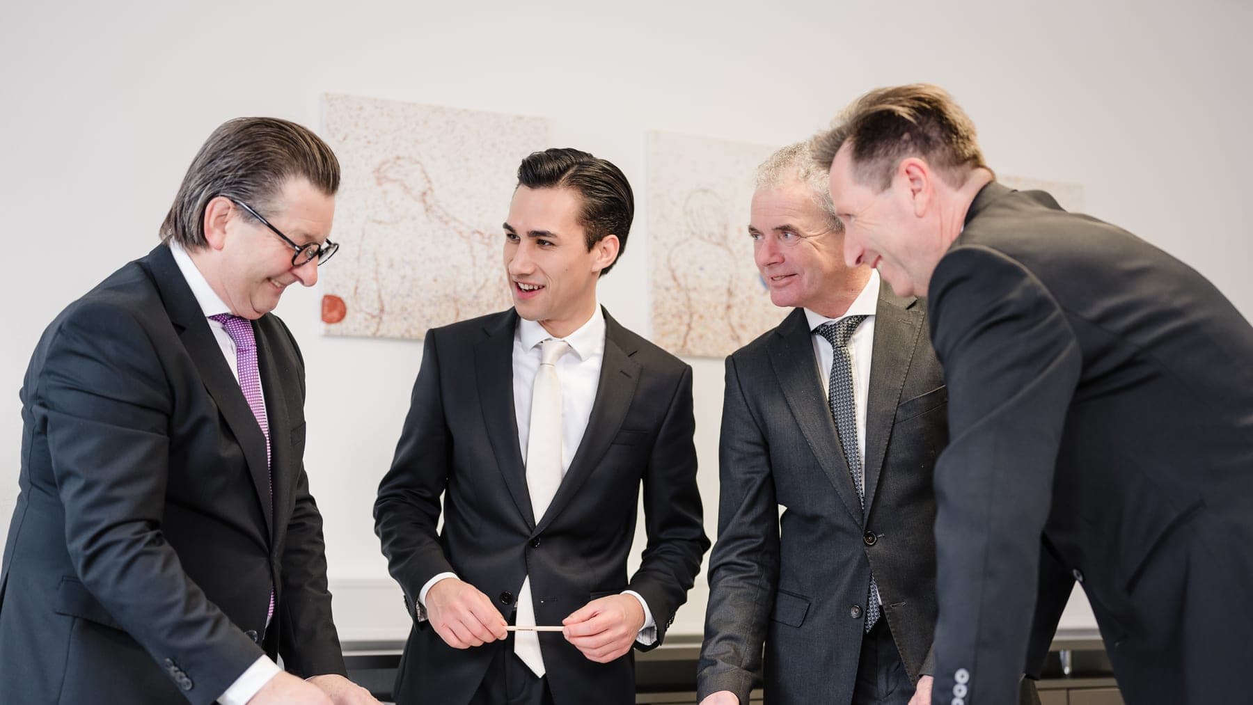 Vier Männer besprechen Pläne am Tisch — Projektgespräch zu einer Gewerbeimmobilie