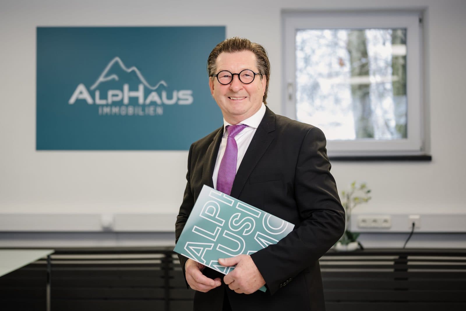 Michael Bauer mit der gedruckten Ausgabe des ALPHAUS-Marktberichts im Büro in Bad Reichenhall