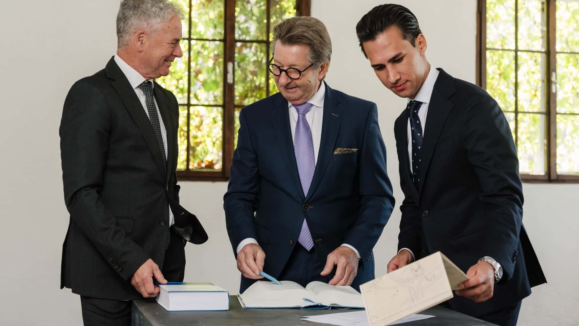 Drei Berater von ALPHAUS Immobilien prüfen am Tisch einen Lageplan — Baurecht gehört vor die Vermarktung