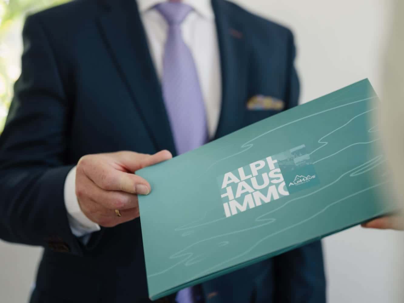 Berater von ALPHAUS Immobilien überreicht die Verkaufsmappe